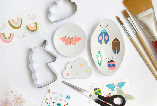 Assorted trinket dish crafting supplies including butterflies rainbows cloud shapes and paint brushes.