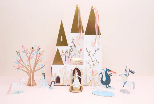 Pastel princess castle centerpiece with paper towers and fairy tale figures on a pink backdrop