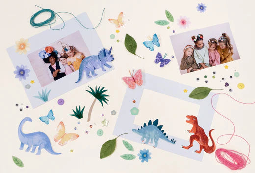 Craft space with photos butterflies dinosaurs leaves and colorful decorations around a blank picture frame