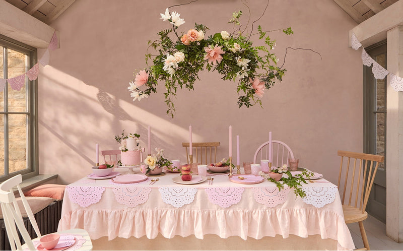 Pastel pink Mother's Day tablescape with floral centerpiece, candles and a lace table runner