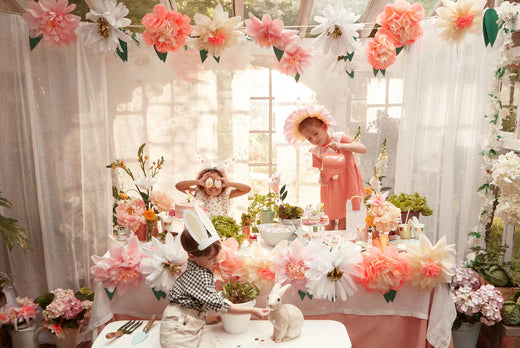 Children in bunny ears at a pastel Easter party with a flower garlanded table