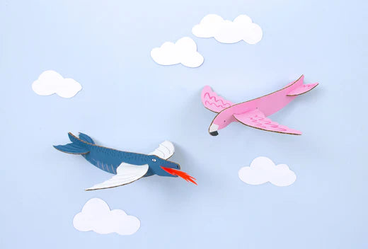 Colorful paper birds soaring through a pale blue sky with fluffy white clouds