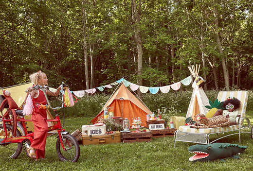Outdoor forest summer party setup with a teepee tent bunting and a giant crocodile inflatable beside a picnic area