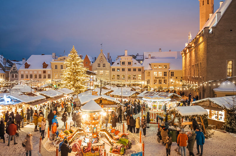 Snowy European Christmas market scene with twinkling lights and a central festive tree