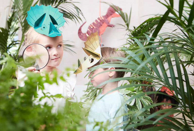 Children with dinosaur hats in a lush, green setting