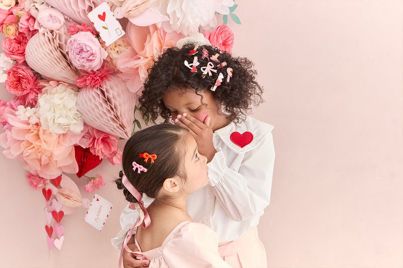 Two children with hair clips and paper decorations.