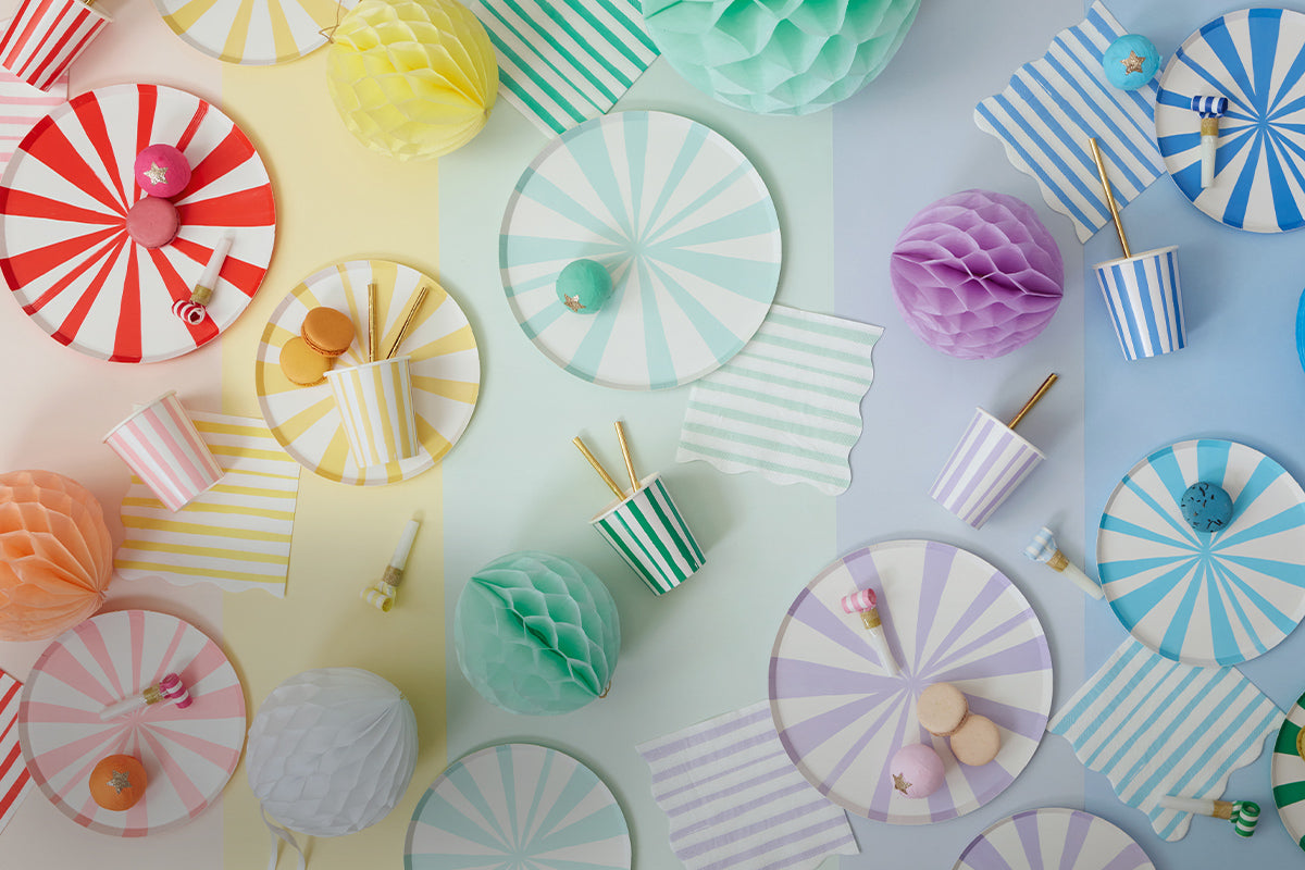 A rainbow display of pinwheel stripe plates, cups, and napkins.