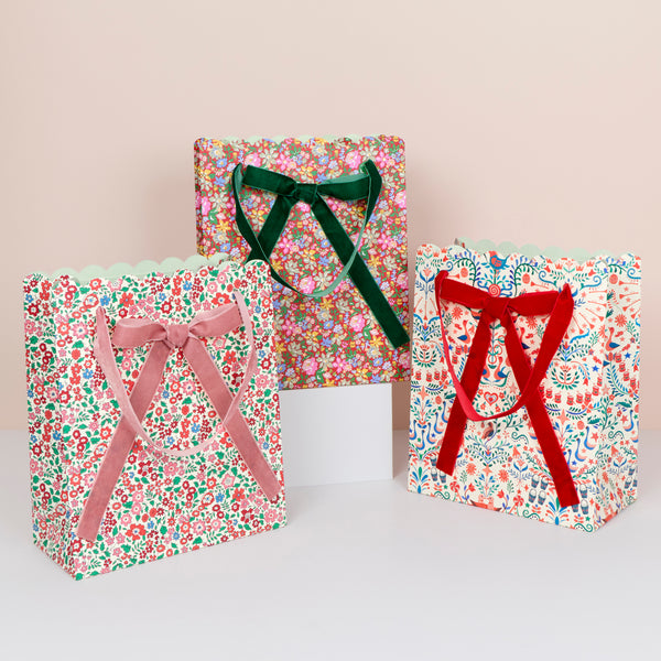 Our paper Christmas gift bags feature beautiful Liberty print designs for an elegant look, with three designs, velvet ribbon bows and handles. Image1