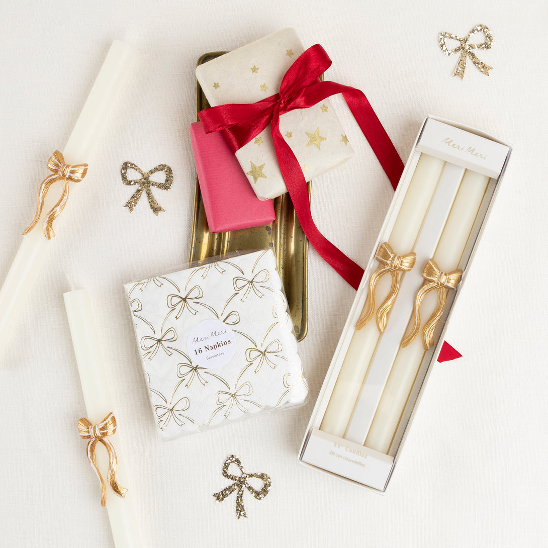 Our golden Christmas host gift set includes two table candles, with gold stripy bow details, and a pack of paper napkins with gold bow designs. 