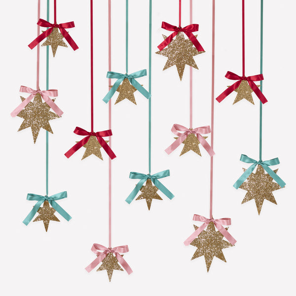 Our Christmas star decorations come in a set of 12, with 3 sizes. Covered with gold glitter, topped with ribbon bows, they are super stylish. Image1