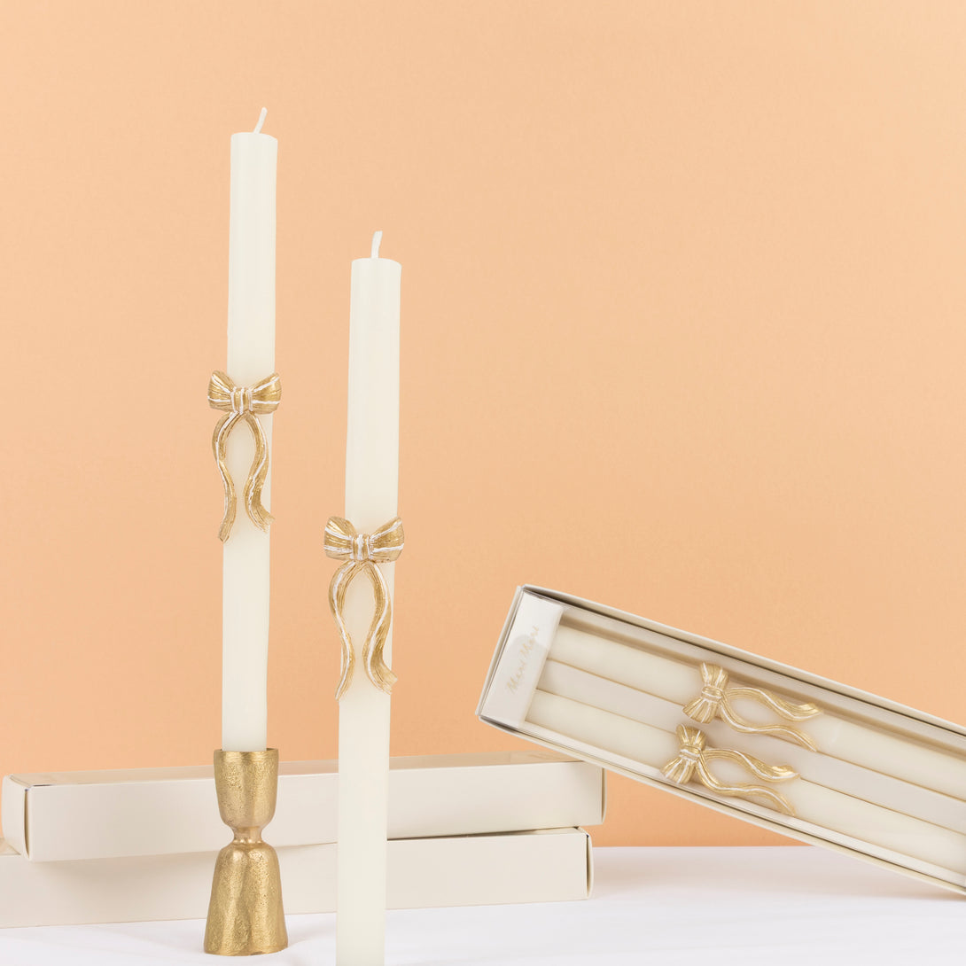 Our golden Christmas host gift set includes two table candles, with gold stripy bow details, and a pack of paper napkins with gold bow designs. 