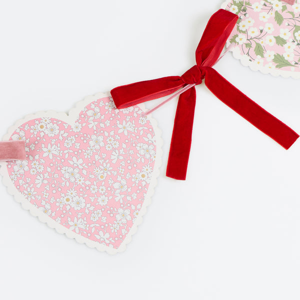 Our Valentine's Day garland feature paper hearts with floral Liberty print designs and pink and red luxe velvet bows. Image3