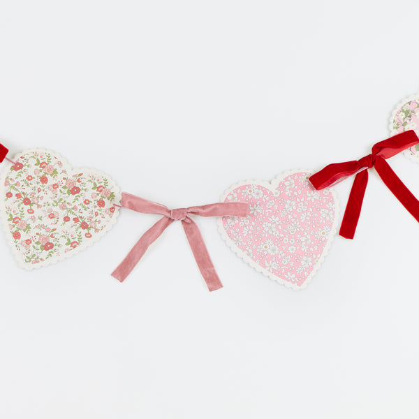 Our Valentine's Day garland feature paper hearts with floral Liberty print designs and pink and red luxe velvet bows. Image3