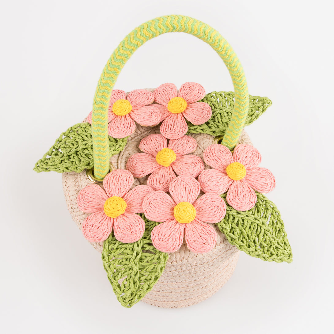 Our woven paper pink basket bag features paper flowers and leaves, a cord handle and a calico lining.