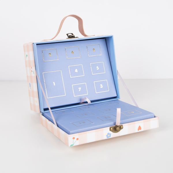 The pink gingham mini suitcase opens to reveal numbered trays filled with enamel charms, tassels and a gold tone necklace. Image4