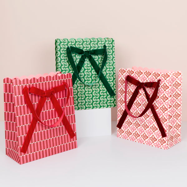 Our medium Christmas gift bags, made from premium paper, feature Molly Mahon block print designs with velvet bows and handles. Image1
