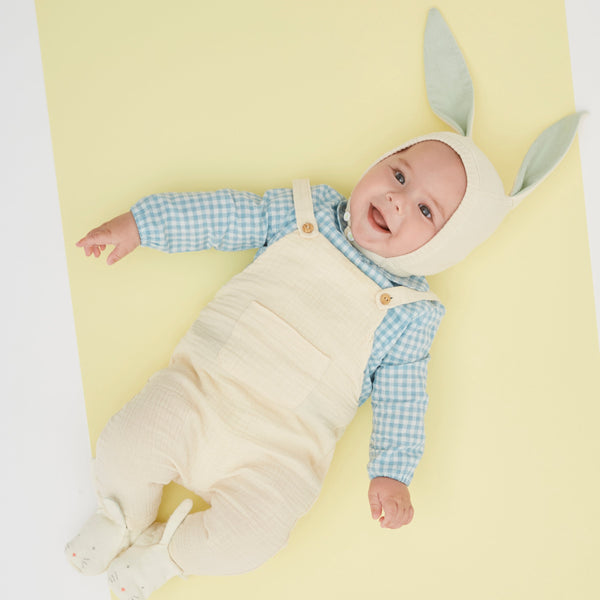 This organic cotton bunny bonnet has a shimmering peach inner on the ears, and an ivory coloured button fastening. Image6