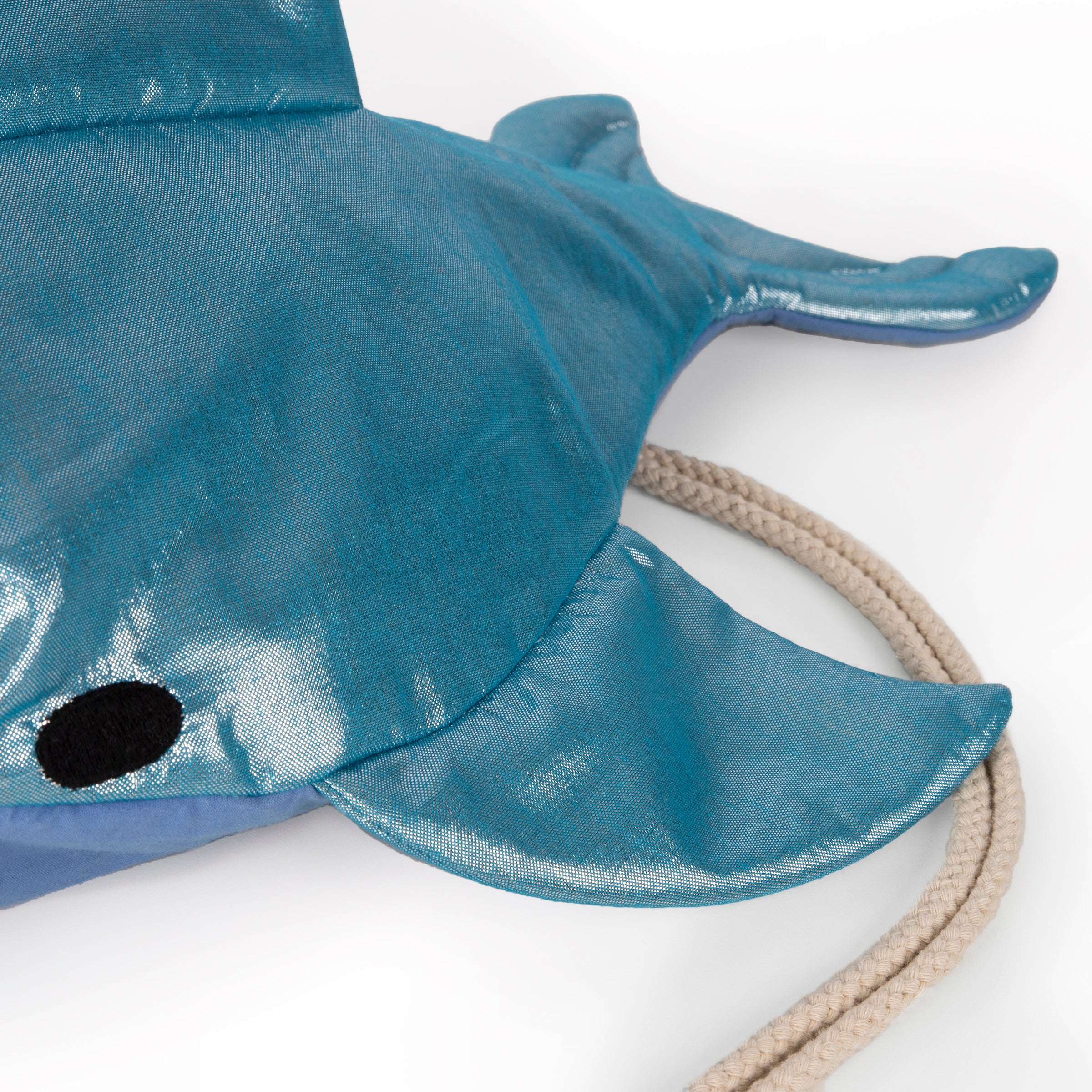 This shiny shark is  a backpack crafted from blue lamé fabric with a cotton lining and cord straps.